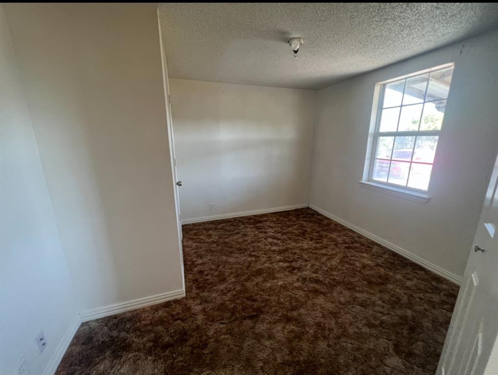 3133 Tbd County Road Lone Oak, TX 75453 - Photo 5 of 21 Spacious room featuring a large window, neutral wall paint, textured ceiling, and brown carpeting