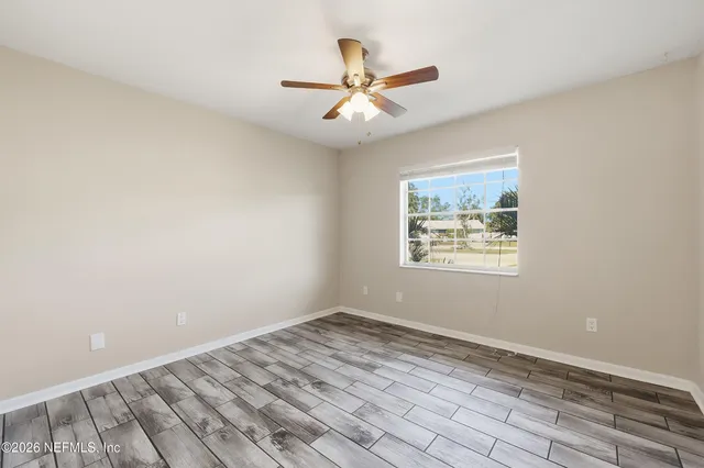 an empty room with a window and ceiling fan