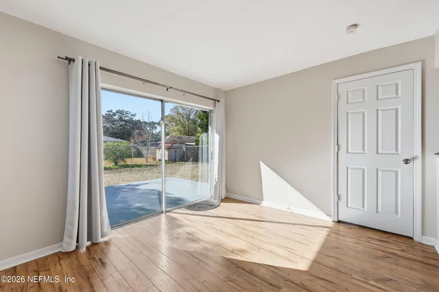 a view of an empty room with wooden floor and a window