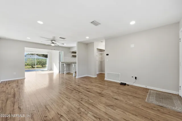 a view of an empty room with wooden floor and a window