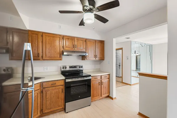 a kitchen with stainless steel appliances granite countertop a refrigerator a sink dishwasher a stove and white countertops with wooden floor