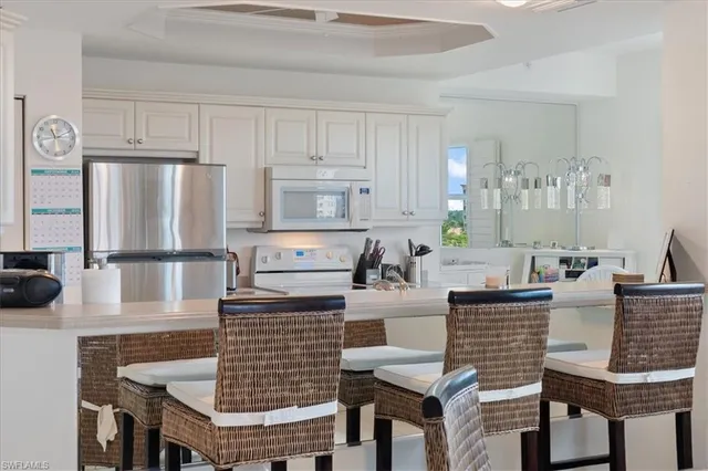 a large white kitchen with stainless steel appliances a sink a stove and cabinets