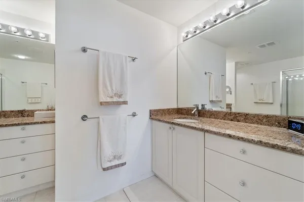 a bathroom with a granite countertop sink a shower and a mirror