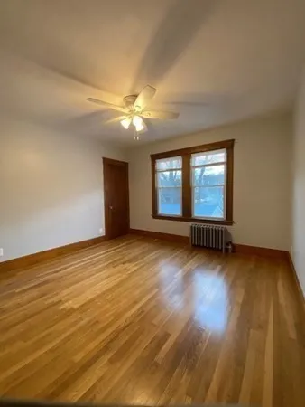 a view of empty room with wooden floor and fan