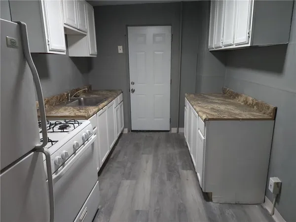 a kitchen with granite countertop a sink a stove oven and cabinets
