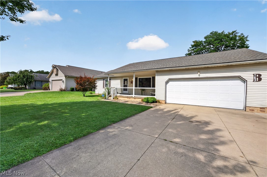 763 Lockwood Road Barberton, OH 44203 - Photo 2 of 24 Attached two-car garage with sectional door, concrete driveway, covered entry porch, and partial landscaping
