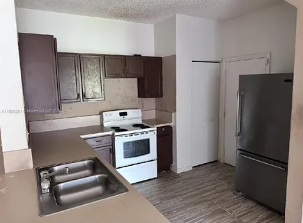 a kitchen with a refrigerator stove and wooden cabinets