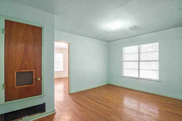 an empty room with wooden floor and windows
