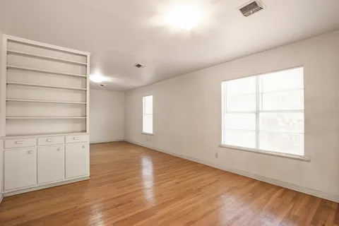 an empty room with wooden floor closet and windows