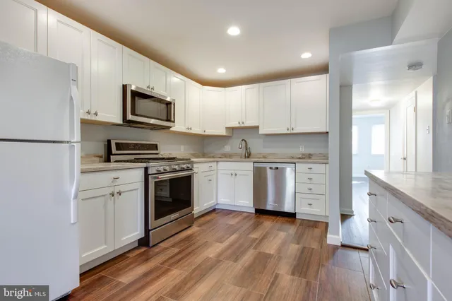 a kitchen with stainless steel appliances a white stove top oven a sink and a refrigerator