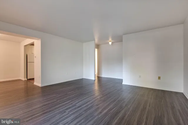 a view of an empty room with wooden floor and closet