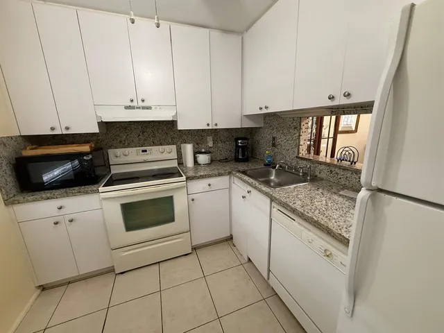 a kitchen with granite countertop white cabinets stainless steel appliances and a sink