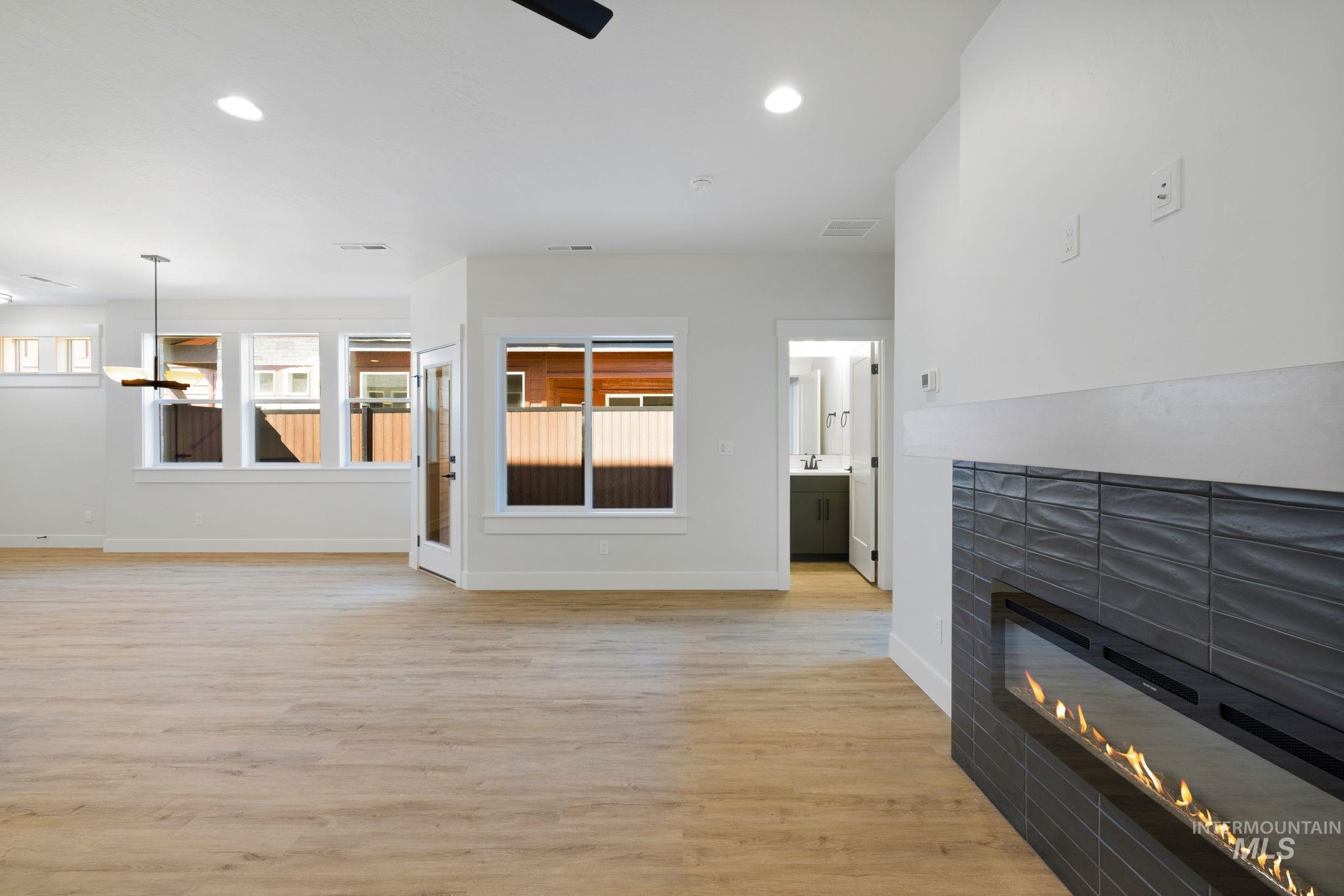 24 Bridger Street Cascade, ID 83611 - Photo 16 of 39 Unfurnished living room with light wood-type flooring, a tile fireplace, recessed lighting, and a chandelier