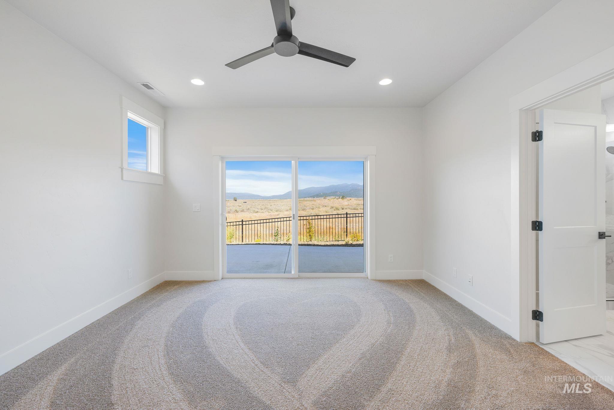 24 Bridger Street Cascade, ID 83611 - Photo 20 of 39 Unfurnished room featuring light carpet, recessed lighting, a mountain view, and a ceiling fan