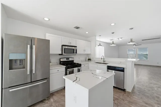 a kitchen with stainless steel appliances a sink stove refrigerator and cabinets