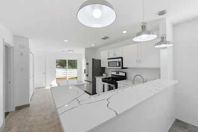 a kitchen with stainless steel appliances a refrigerator sink and white cabinets