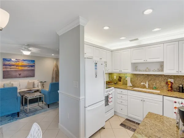 a kitchen with granite countertop a refrigerator a stove a sink and white cabinets