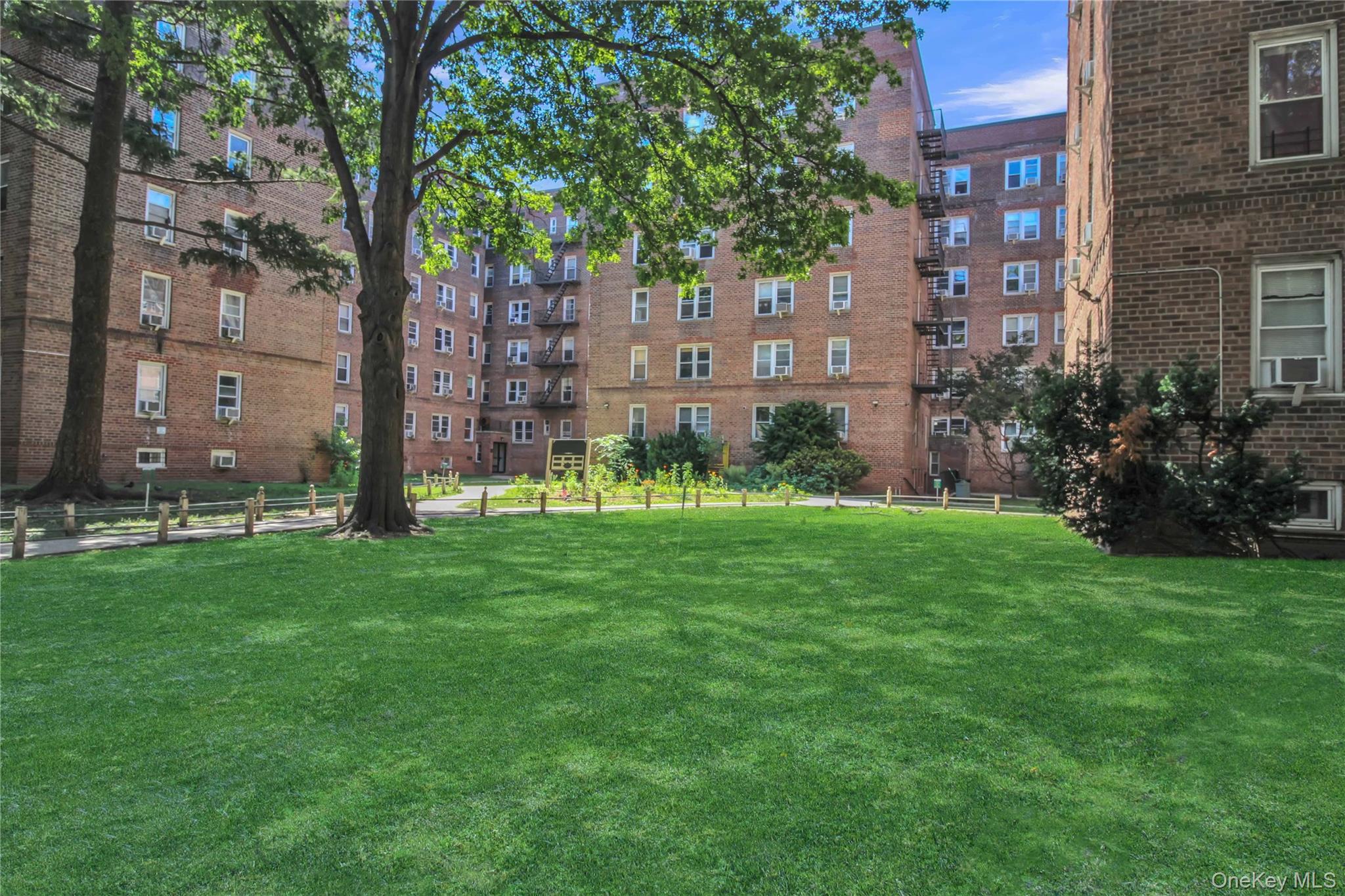 35-40 75th Street, Unit 5B Queens, NY 11372 - Photo 18 of 20 a view of a brick house with a big yard and large trees