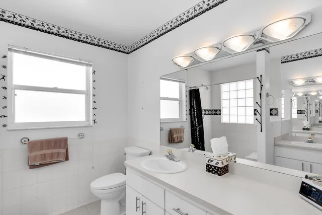 a bathroom with a double vanity sink toilet and a mirror