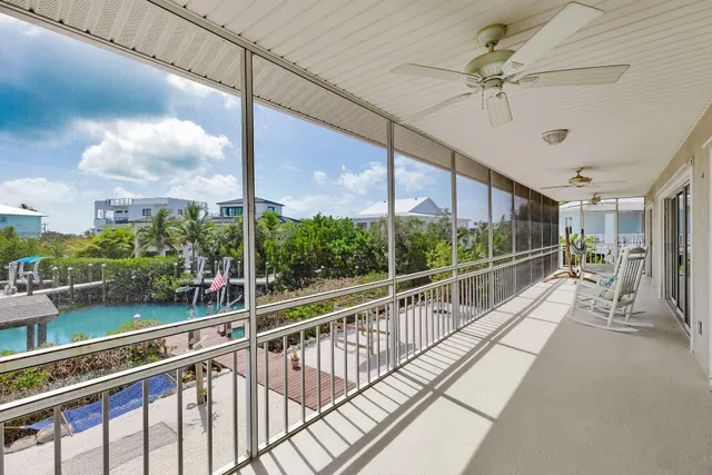 a view of a lake with lawn chairs and large trees