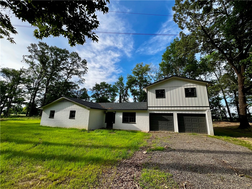 213 Carter Road Pottsville, AR 72858 - Photo 1 of 41 White brick exterior with a vertical siding accent, featuring a two-car garage with dark paneled doors