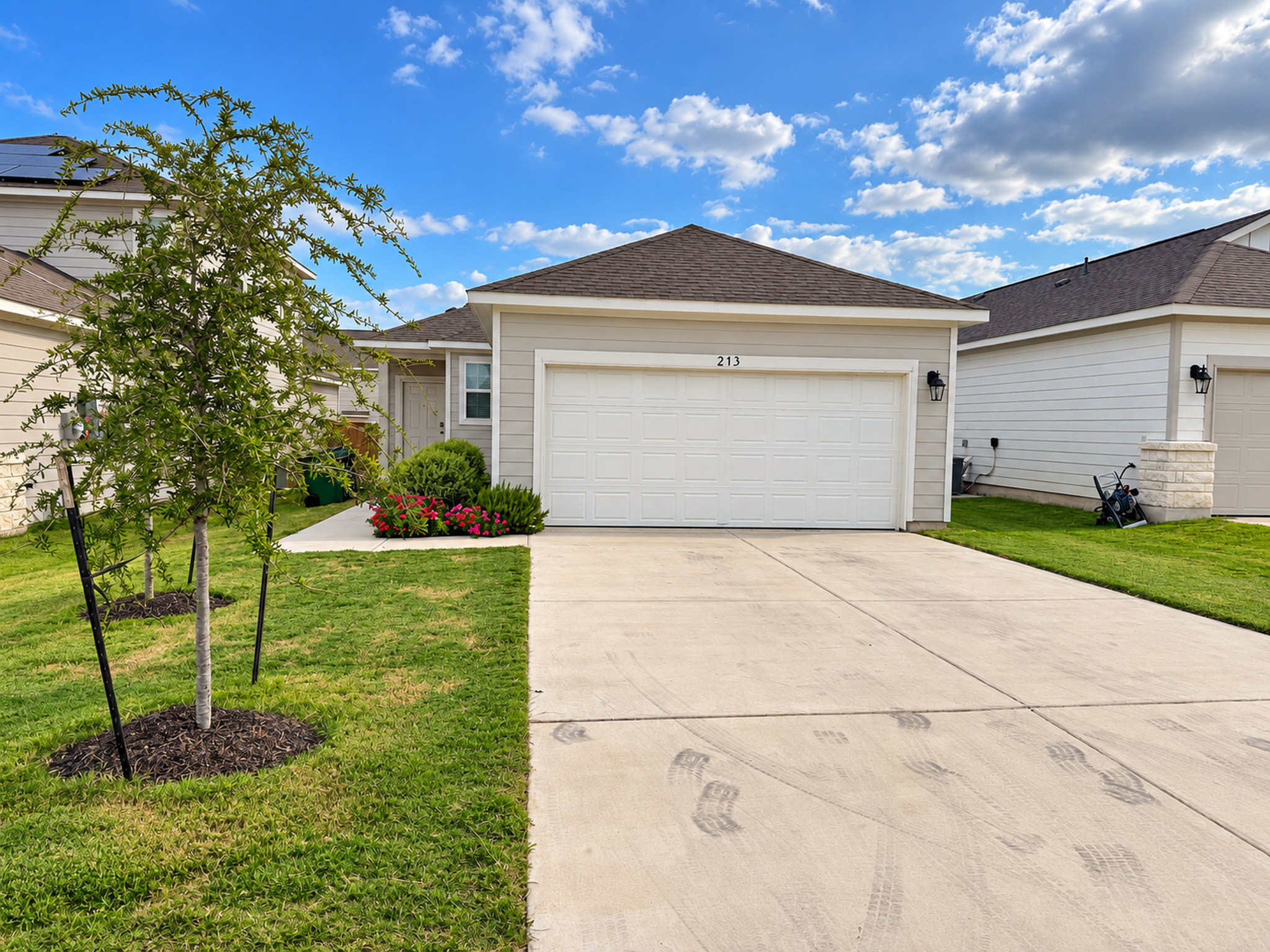 A spacious concrete driveway leads to a modern single-story residence with a two-car garage.