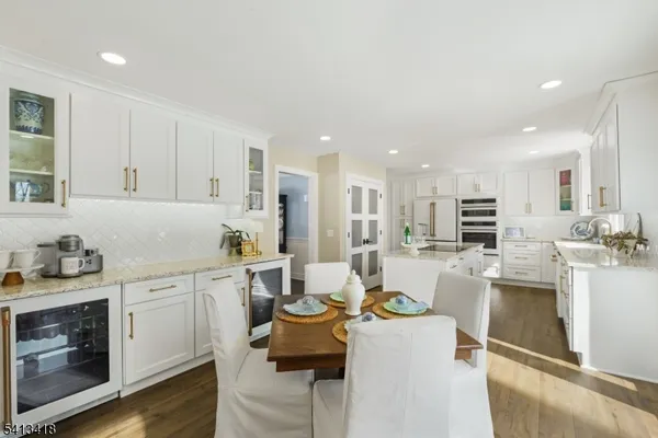 a view of a kitchen with kitchen island white cabinets and stainless steel appliances