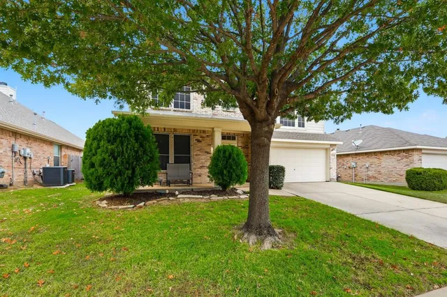 a view of a house with a yard and a large tree