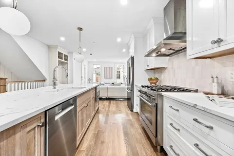 a kitchen with stainless steel appliances granite countertop a sink a stove and a wooden floors