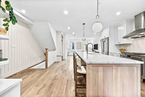a very nice looking kitchen with a dining table chairs wooden floor and a kitchen view