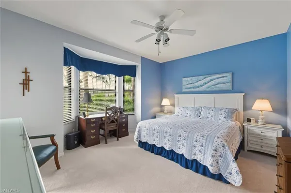 a bedroom with a bed a chandelier and a large window
