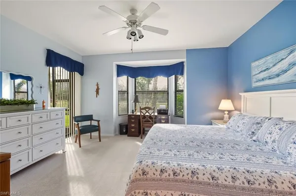 a bedroom with a large bed and a chandelier fan