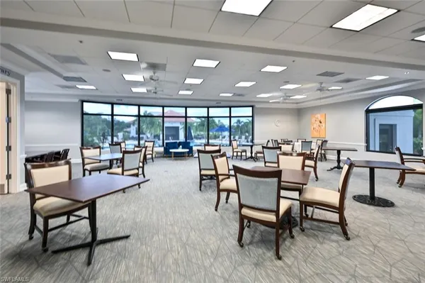 a dining room with lots of tables a large window and chairs