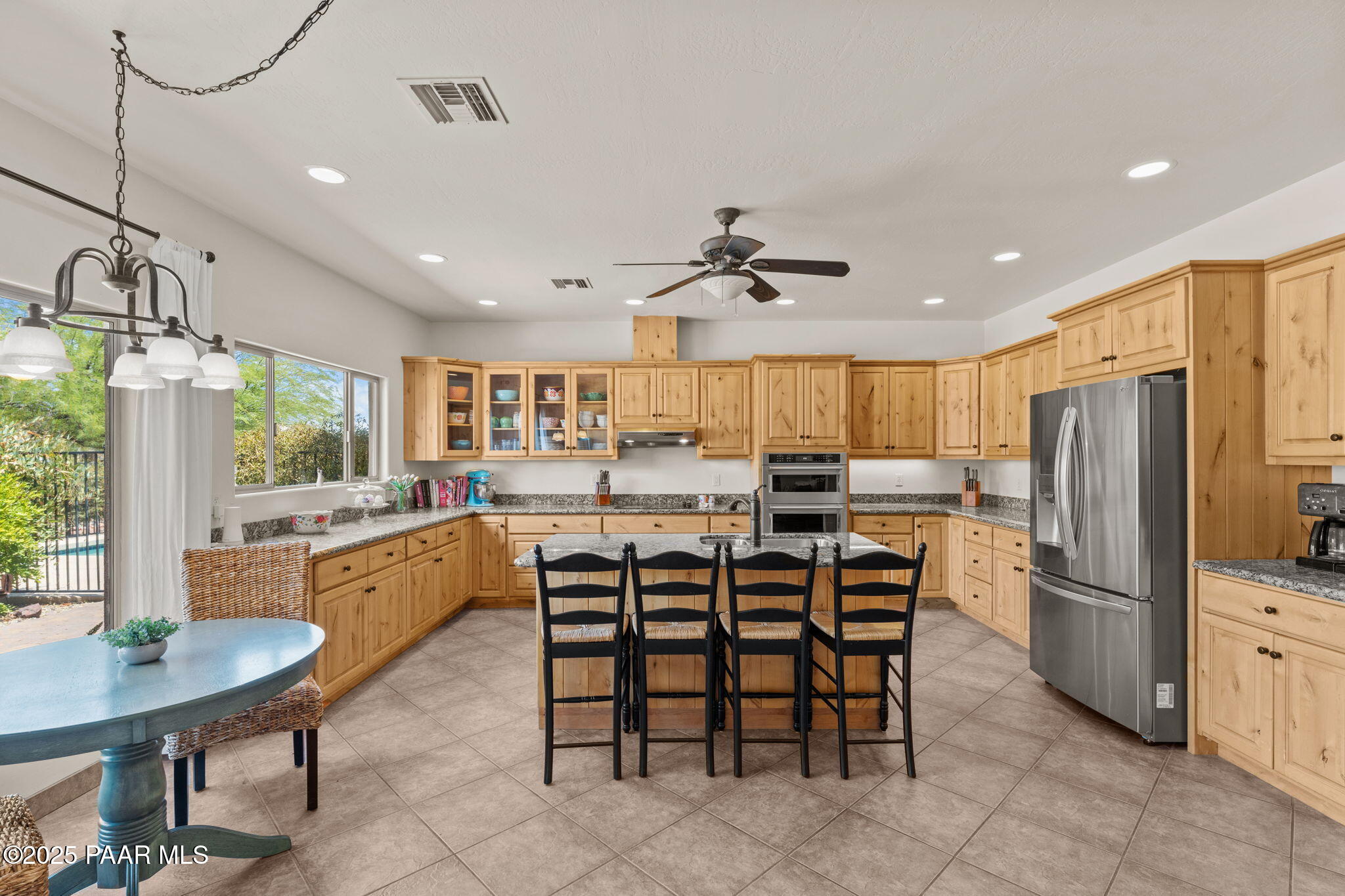 2100 West Silverlode Drive Wickenburg, AZ 85390 - Photo 15 of 51 a kitchen with stainless steel appliances kitchen island granite countertop a table chairs and a refrigerator
