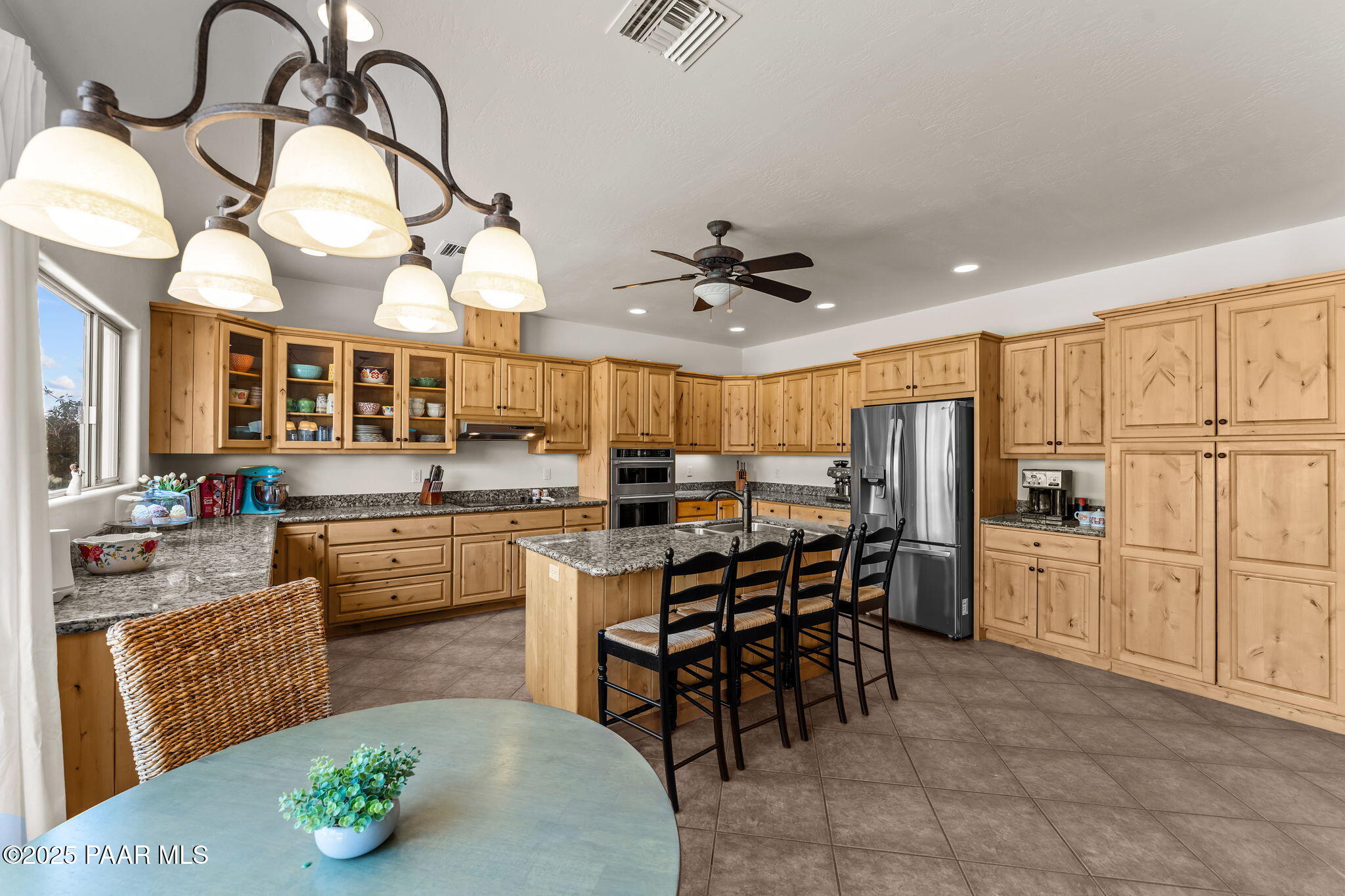 2100 West Silverlode Drive Wickenburg, AZ 85390 - Photo 17 of 51 a kitchen with stainless steel appliances kitchen island granite countertop a stove a refrigerator a dining table and chairs with wooden floor