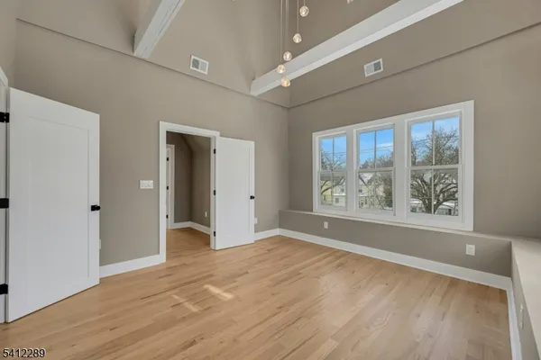 a view of an empty room with window and wooden floor