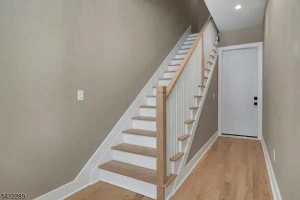 a view of staircase with wooden floor and white walls