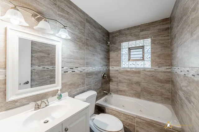 a bathroom with a bathtub shower sink vanity mirror and toilet