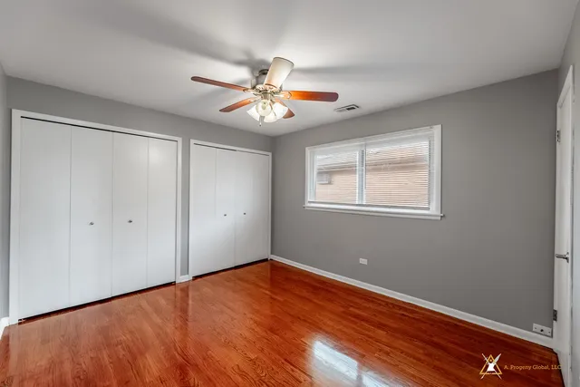 a view of an empty room with window and chandelier fan