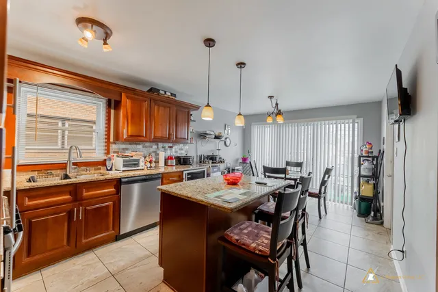 a open kitchen with stainless steel appliances granite countertop wooden cabinets a dining table and chairs