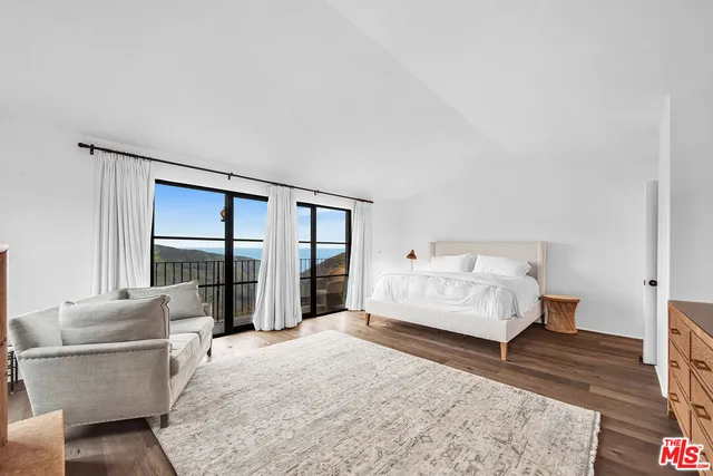 a bedroom with a bed couch and wooden floor