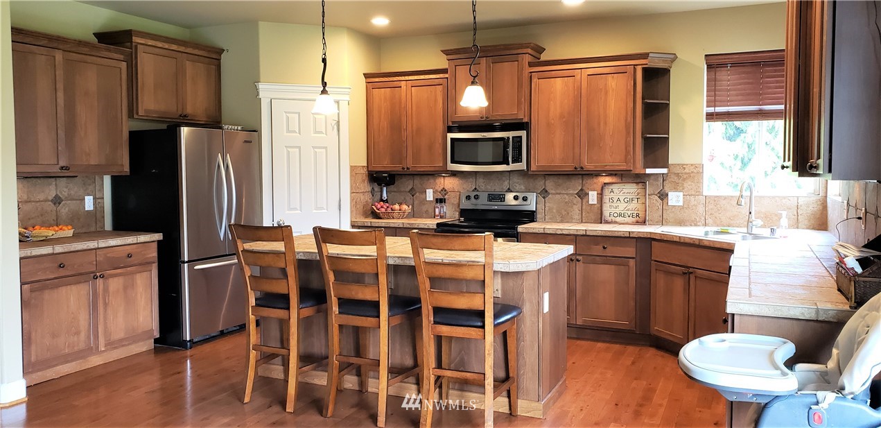 17834 Kenworth Lane Southwest Rochester, WA 98579 - Photo 6 of 29 a kitchen with stainless steel appliances kitchen island granite countertop a sink refrigerator and cabinets