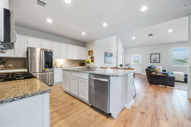 a kitchen with a refrigerator a sink a stove a microwave a counter top space and cabinets