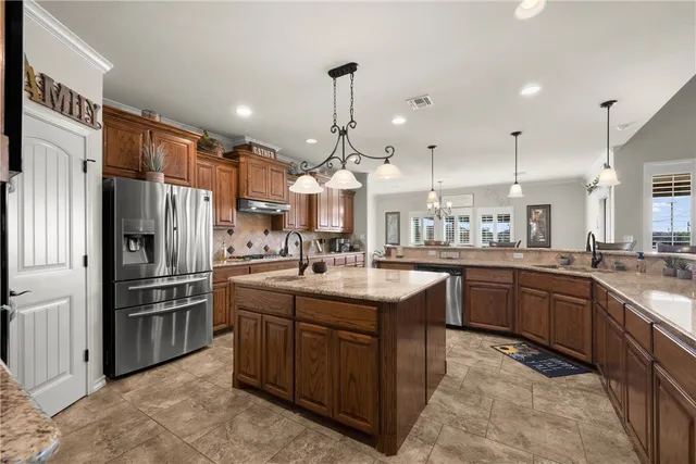 a kitchen with kitchen island granite countertop a sink stove and refrigerator