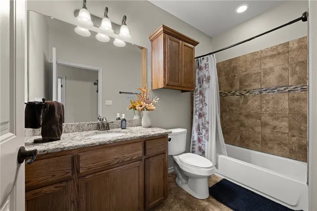 a bathroom with a granite countertop sink a toilet and shower