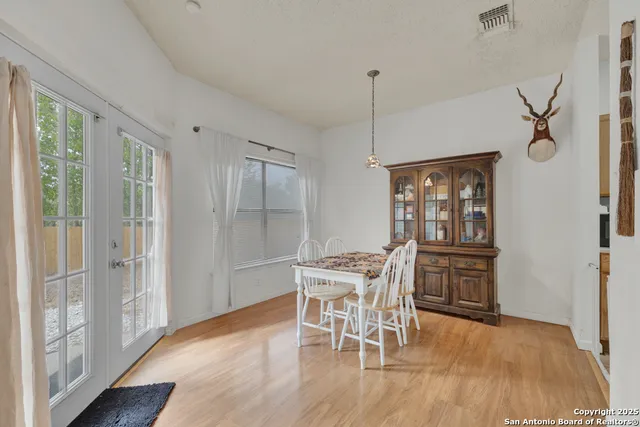 a dining room with furniture wooden floor a potted plant and a chandelier