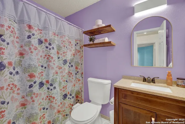 a bathroom with a granite countertop toilet sink and mirror