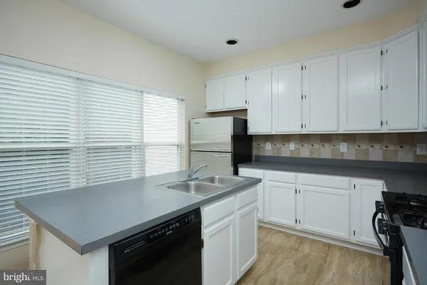 a kitchen with granite countertop a sink a stove and cabinets