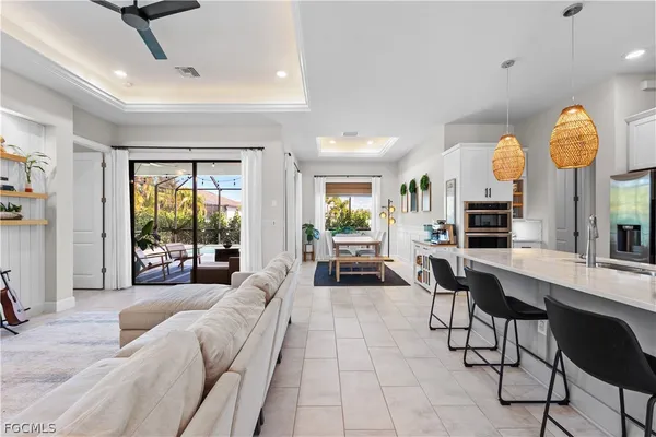 a living room with furniture a chandelier fan and a large window