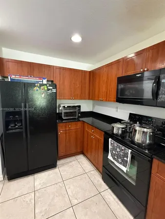 a kitchen with granite countertop a refrigerator and a stove top oven